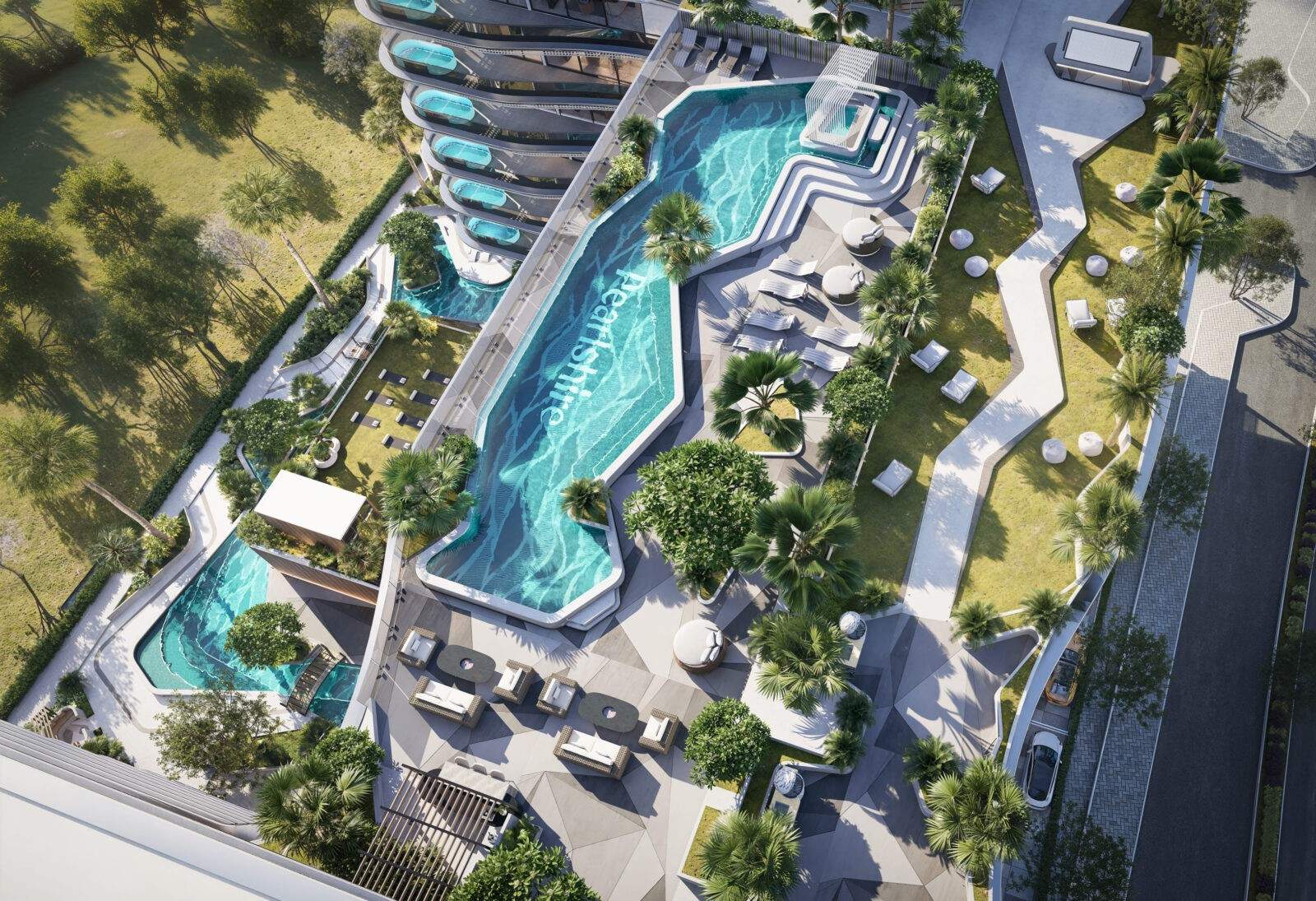 Letecký pohled na hlavní bazén Bond Enclave s lazy river, lehátky a zelenou terasou